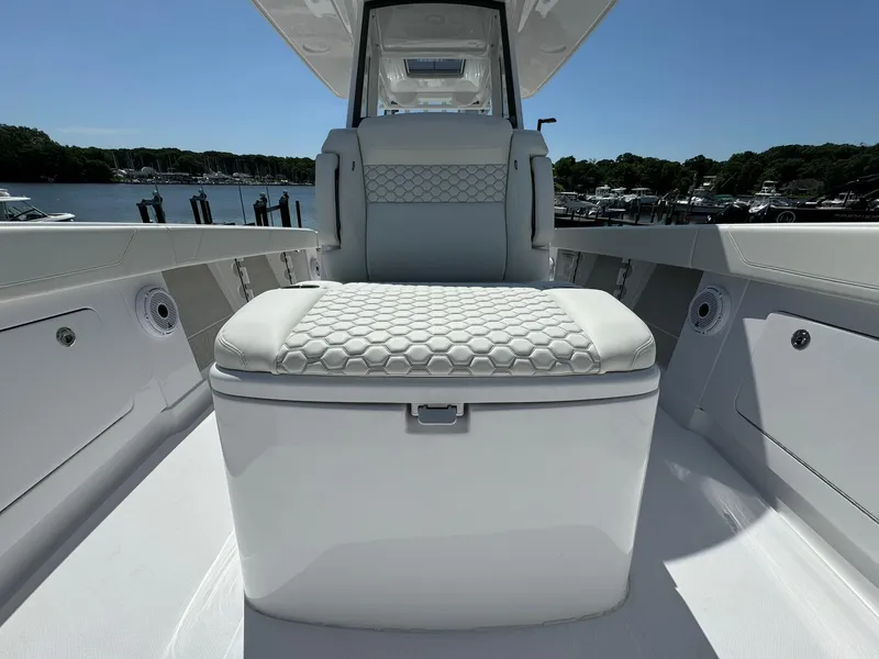 Slide: The Image of 2024 Jupiter 340LS boat interior with cushioned seating and storage, docked at a marina. - 19