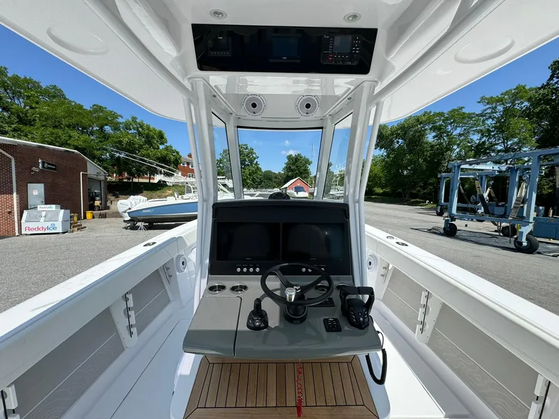 Slide: The Image of 2024 Jupiter 340LS boat cockpit with steering wheel and control panel, docked outdoors. - 12