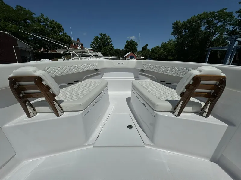 Slide: The Image of 2024 Jupiter 340LS boat interior with white cushioned seating and wooden accents. - 16