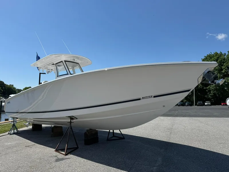 Slide: The Image of 2024 Jupiter 340LS boat on stands, white hull, clear sky background. - 2