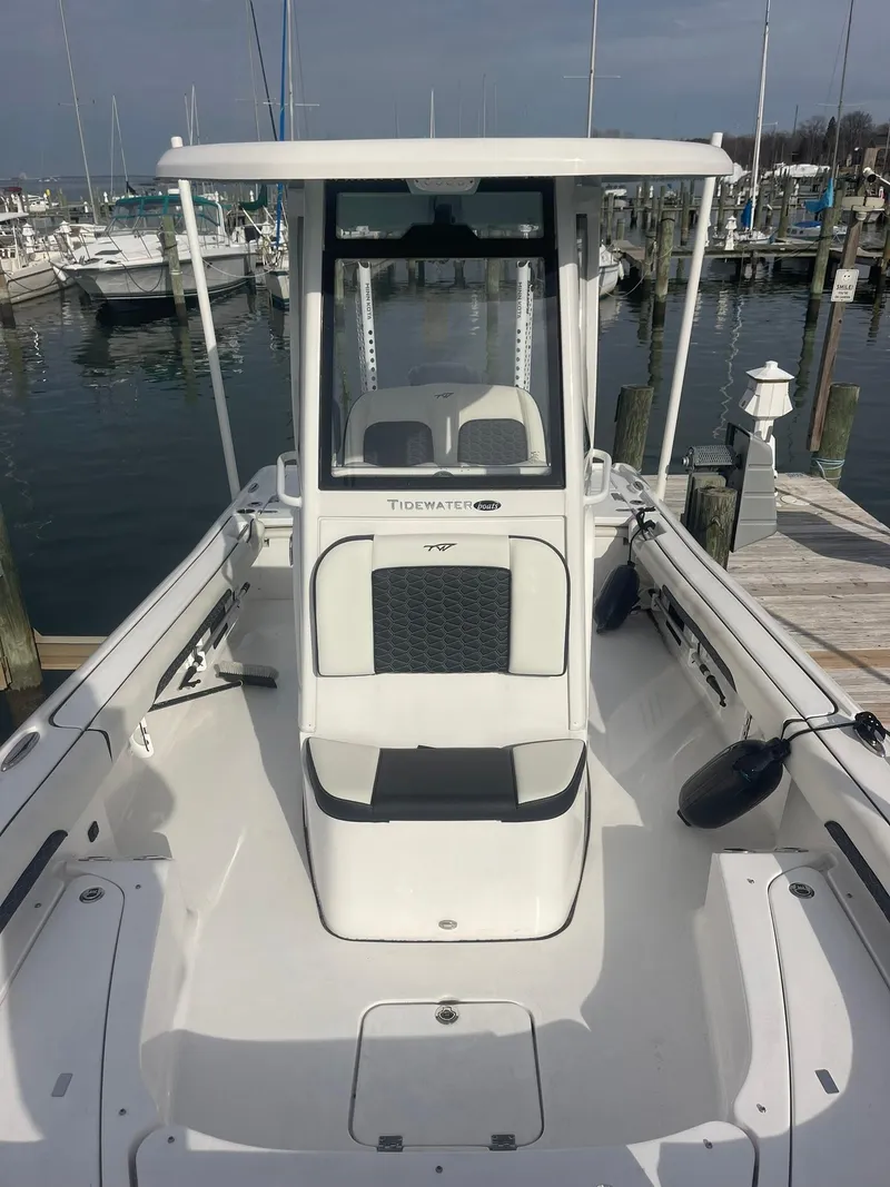 Slide: The Image of 2024 Tidewater 2500 Carolina Bay boat on calm water with marina background. - 2