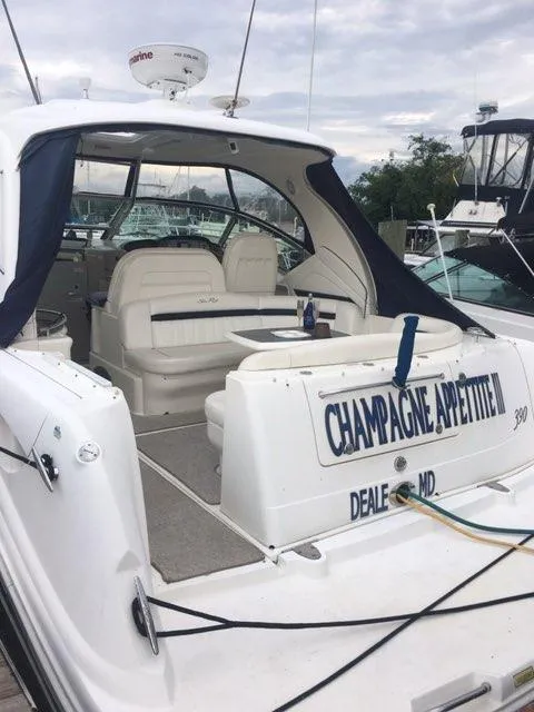 Slide: The Image of 2004 Sea Ray 390 Sundancer boat with sleek blue hull, docked under clear sky. - 5