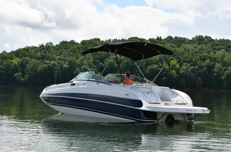Slide: The Image of 2005 Four Winns 234 Funship boat on a calm lake with lush green trees. - 1