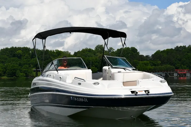 Slide: The Image of 2005 Four Winns 234 Funship boat on a calm lake with lush green background. - 3