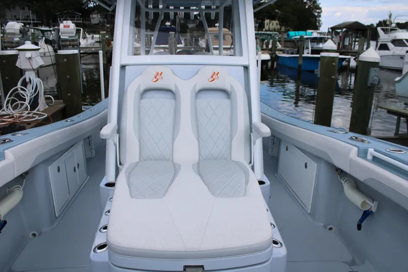 Slide: The Image of 2024 Yellowfin 36 Offshore boat interior with dual cushioned seats at a marina. - 12