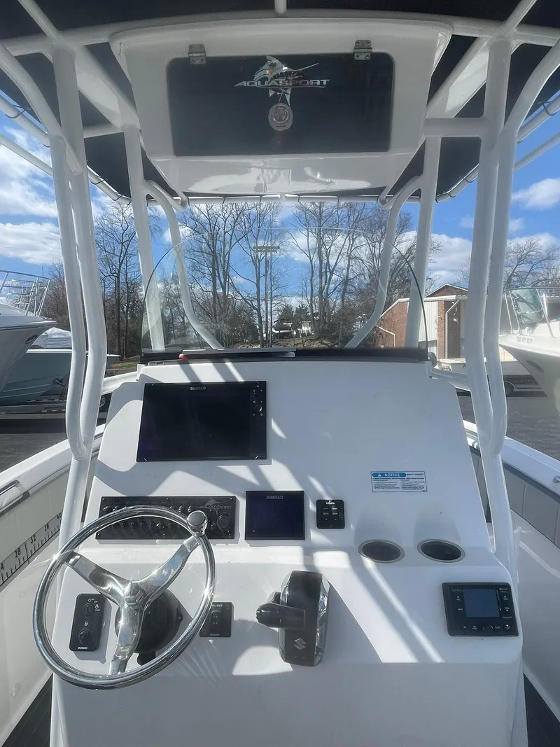 Slide: The Image of 2022 Aquasport 2100 CC boat console with steering wheel and navigation screens. - 14
