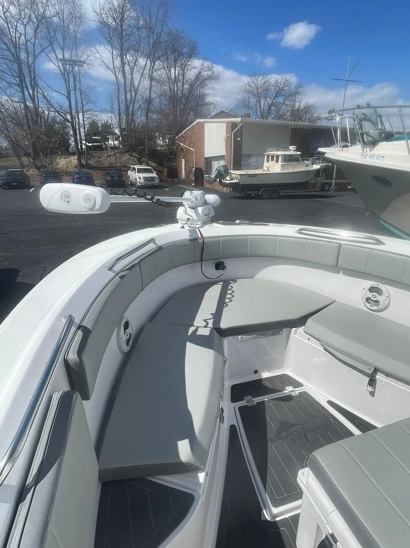 Slide: The Image of 2022 Aquasport 2100 CC boat with spacious seating and modern design, docked outdoors. - 17