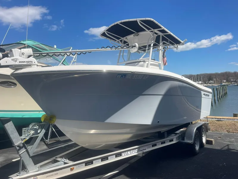 Slide: The Image of 2022 Aquasport 2100 CC boat on trailer, dockside under clear blue sky. - 4