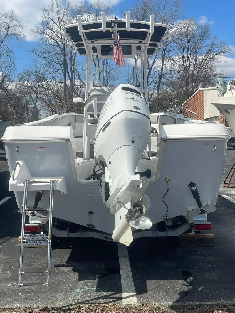 Slide: The Image of 2022 Aquasport 2100 CC boat, rear view, parked outdoors, showcasing outboard motor and ladder. - 7