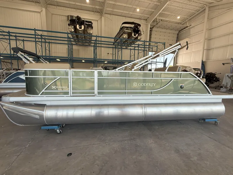 The Image of 2025 Godfrey EX2086SFLX Tritoon boat in a spacious indoor showroom. - 0