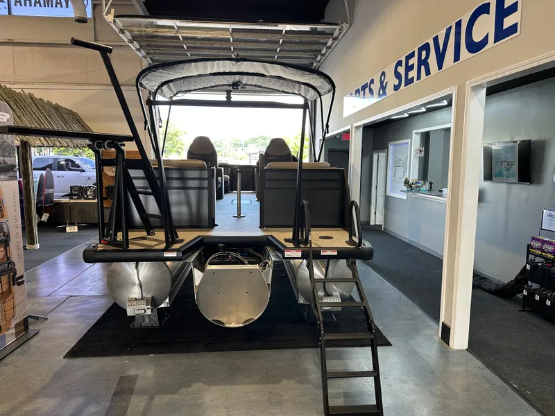 Slide: The Image of 2025 Viaggio Lago X-U pontoon boat displayed in showroom, rear view with ladder and canopy. - 7