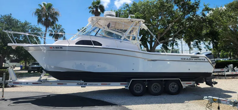 The Image of 2004 Grady-White Marlin 300 boat on trailer, parked outdoors under clear sky. - 0