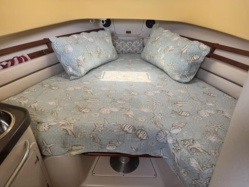 Slide: The Image of 2004 Grady-White Marlin 300 cabin interior with nautical-themed bedding and pillows. - 17
