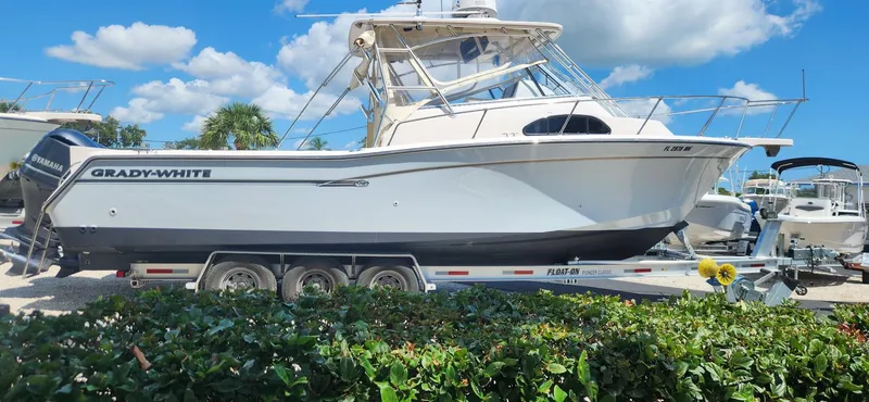 Slide: The Image of 2004 Grady-White Marlin 300 boat on trailer, sunny day, blue sky, lush greenery. - 2