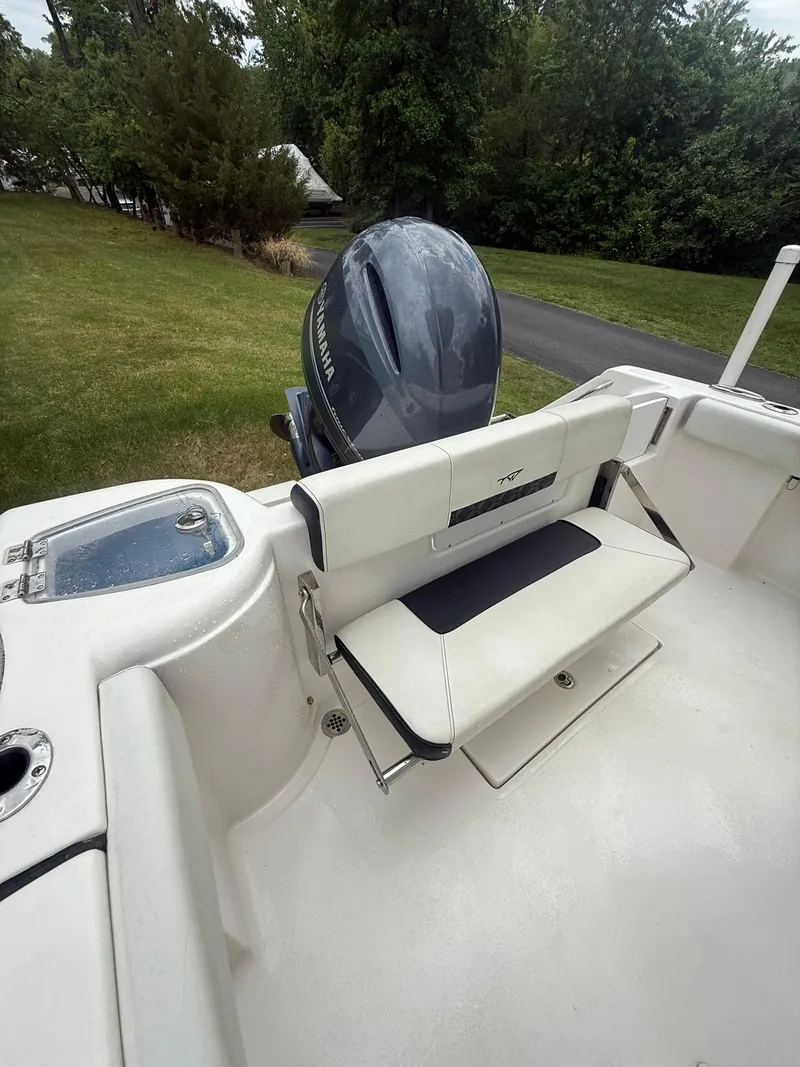 Slide: The Image of 2021 Tidewater 220 CC boat with seating and outboard motor, parked on grass. - 18