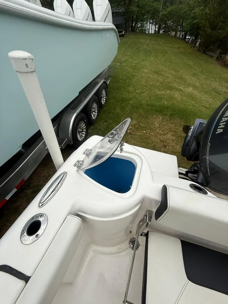 Slide: The Image of 2021 Tidewater 220 CC boat with open storage compartment, parked on grass beside a trailer. - 19