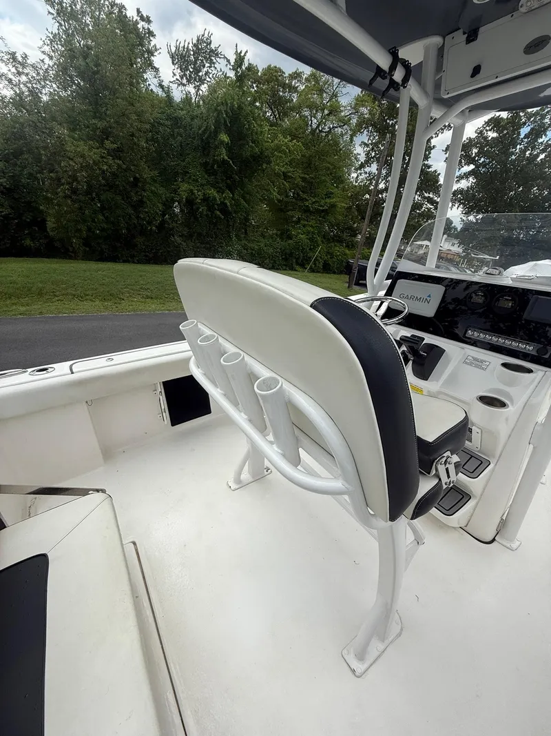 Slide: The Image of 2021 Tidewater 220 CC boat interior with seating and console, surrounded by lush greenery. - 20