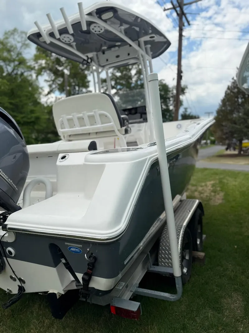Slide: The Image of 2021 Tidewater 220 CC boat on trailer, parked on grass, with T-top and outboard motor. - 27