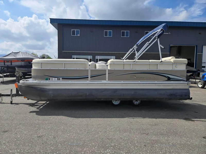Slide: The Image of 2008 Bennington 2050 RL pontoon boat parked outside a building under a cloudy sky. - 1