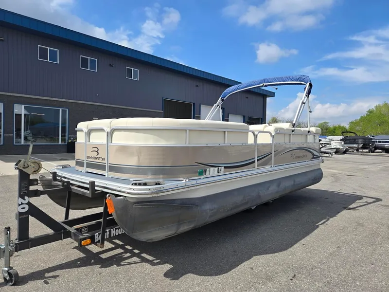 Slide: The Image of 2008 Bennington 2050 RL pontoon boat on trailer, parked outside a building under blue sky. - 2