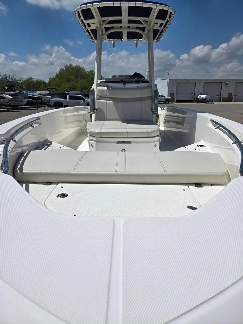 Slide: The Image of 2022 Boston Whaler Dauntless 250 boat interior with seating and T-top under a blue sky. - 7