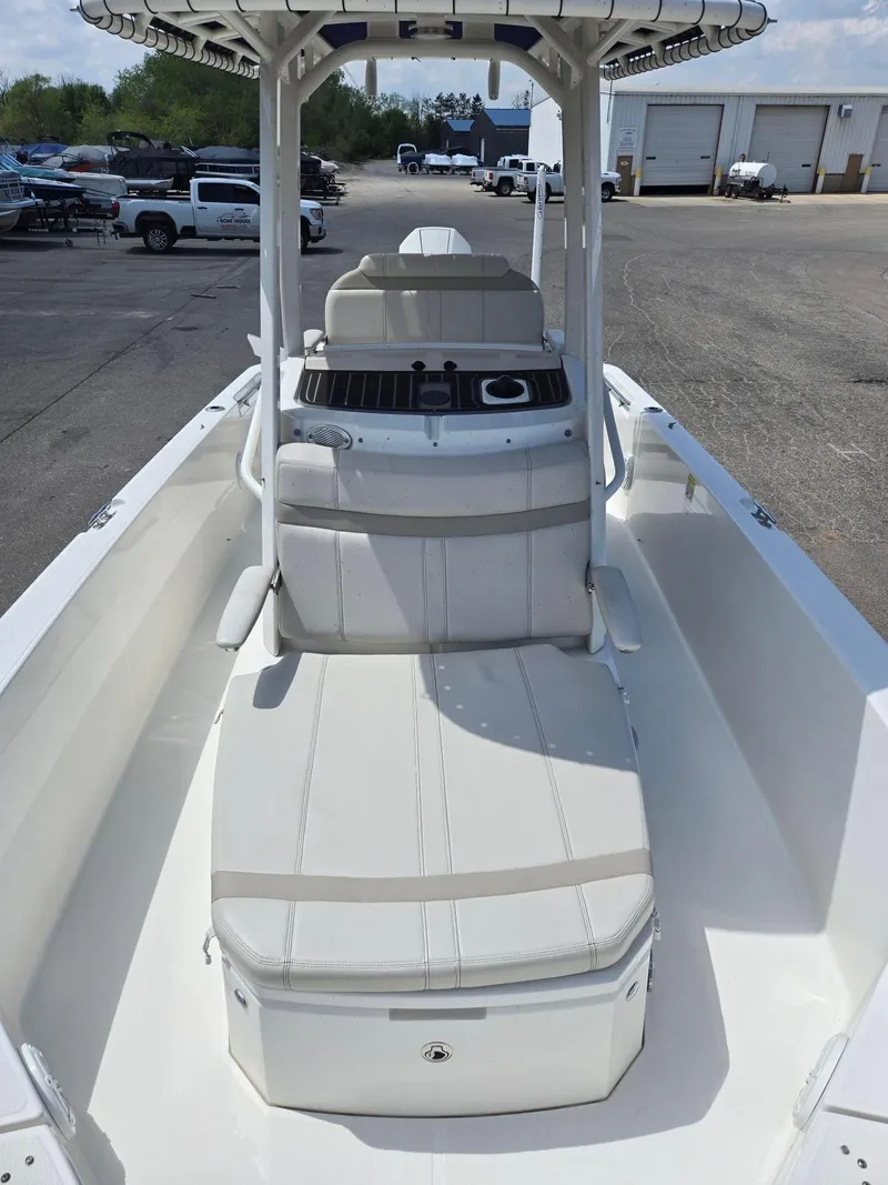 Slide: The Image of 2022 Boston Whaler Dauntless 250 boat interior with seating and console, parked outdoors. - 9