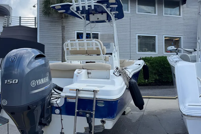 Slide: The Image of 2018 NauticStar 2102 Legacy boat with Yamaha 150 engine, docked near a building. - 2