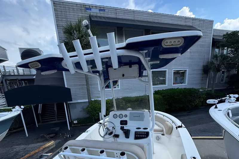 Slide: The Image of 2018 NauticStar 2102 Legacy boat with T-top and console, docked near a building. - 5
