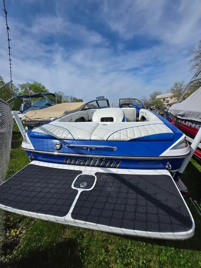 Slide: The Image of 2005 Malibu Response LXi boat with blue and white interior, parked outdoors under a clear sky. - 4