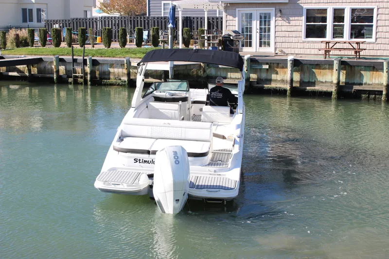 Slide: The Image of 2020 Sea Ray SDX 270 OB boat docked in calm waters near a waterfront house. - 11