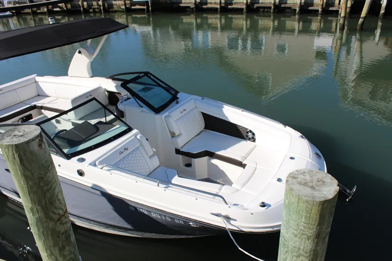 Slide: The Image of 2020 Sea Ray SDX 270 OB boat docked in calm waters, featuring sleek design and spacious seating. - 20