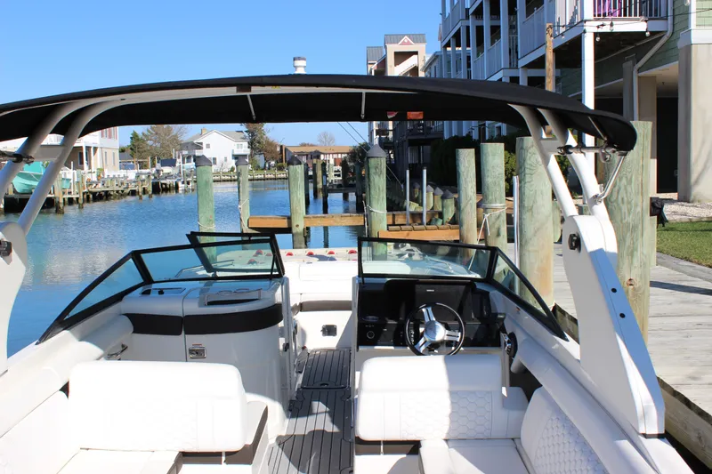 Slide: The Image of 2020 Sea Ray SDX 270 OB boat docked by waterfront homes, featuring spacious seating and sleek design. - 24