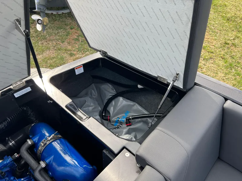 Slide: The Image of 2020 MasterCraft NXT22 boat storage compartment with open lid and visible engine components. - 19