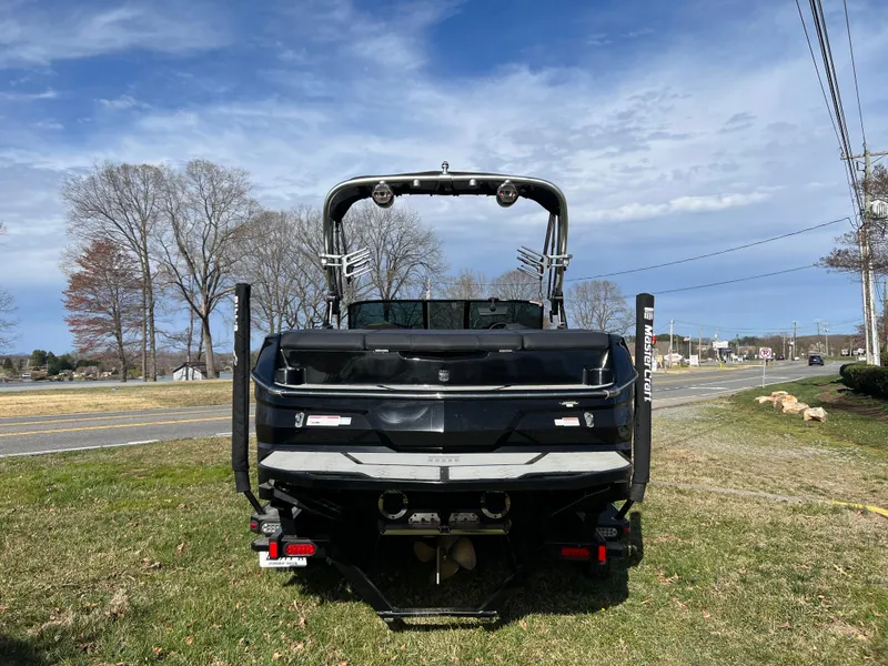 Slide: The Image of 2020 MasterCraft NXT22 boat, rear view, parked on grass under a clear sky. - 2