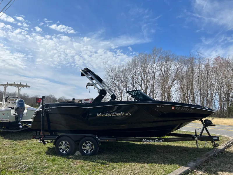 Slide: The Image of 2020 MasterCraft NXT22 boat on trailer under clear blue sky. - 3