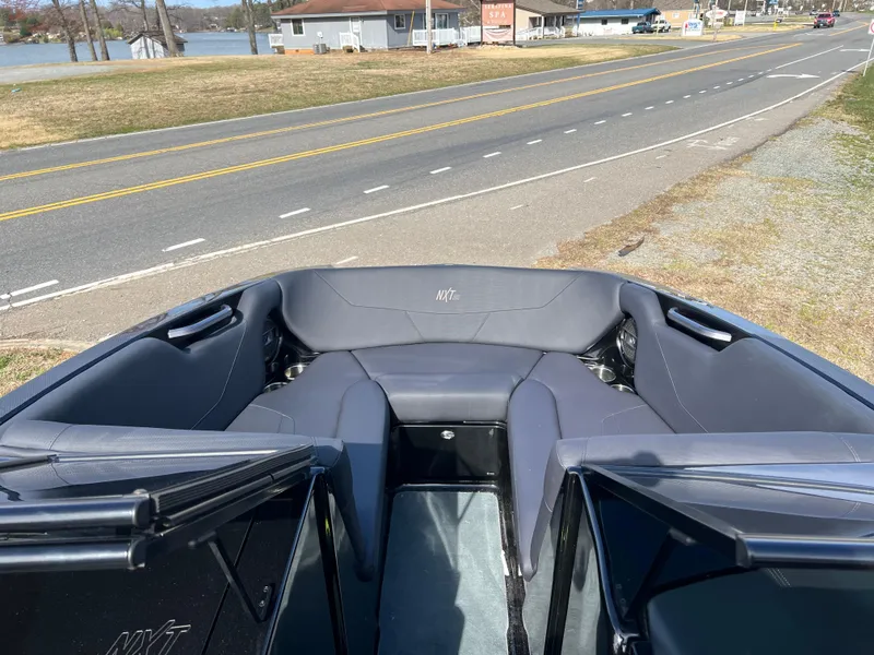Slide: The Image of 2020 MasterCraft NXT22 boat interior with gray seating, parked near a road and lake. - 5