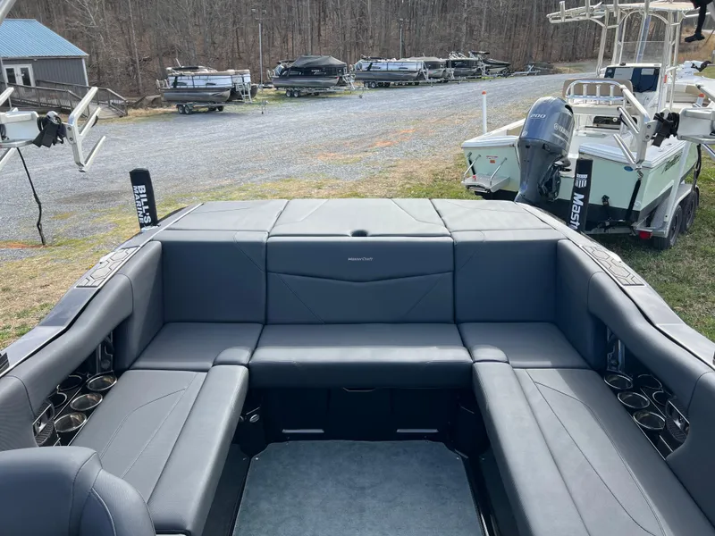 Slide: The Image of 2020 MasterCraft NXT22 boat interior with gray seating and cup holders, parked outdoors. - 9