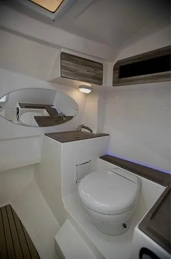 Slide: The Image of 2018 Edgewater 262 CX boat interior with modern bathroom and wooden accents. - 13