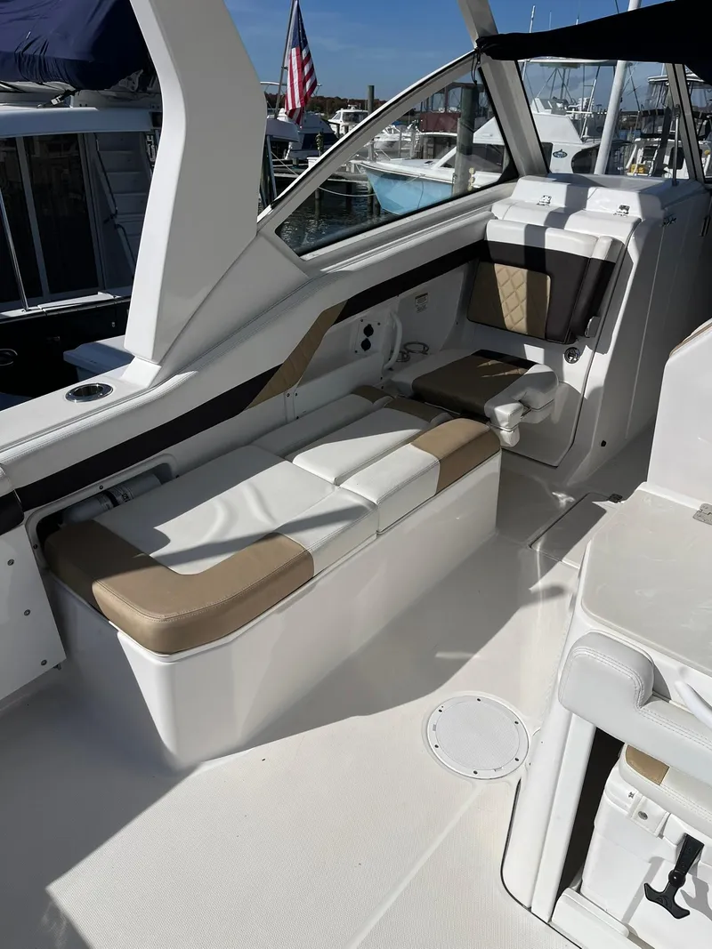 Slide: The Image of 2018 Edgewater 262 CX boat interior with cushioned seating and American flag in background. - 16