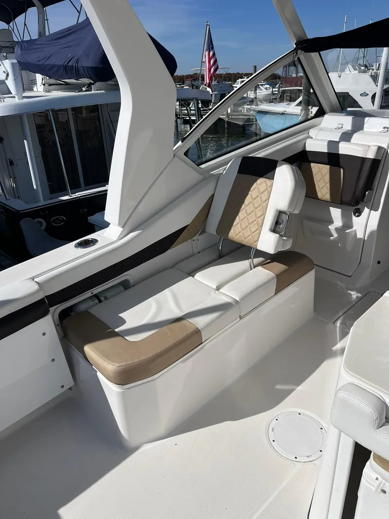 Slide: The Image of 2018 Edgewater 262 CX boat interior with beige seating and marina view. - 17
