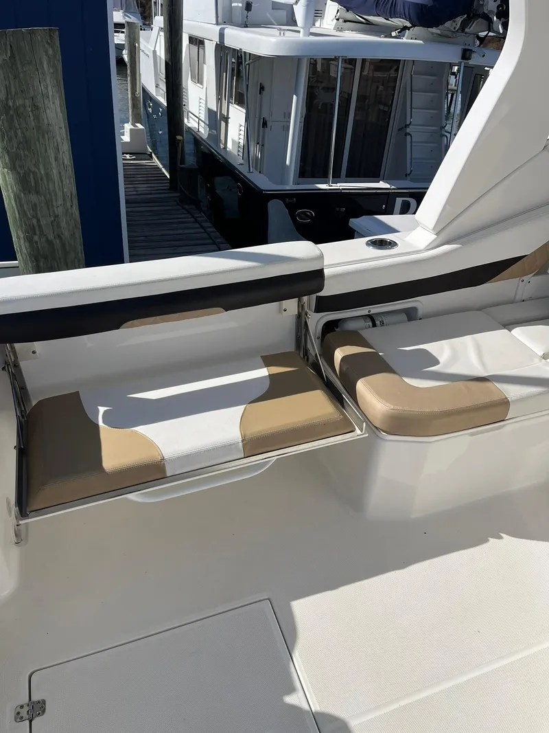 Slide: The Image of 2018 Edgewater 262 CX boat interior with beige seating and docked in a marina. - 18