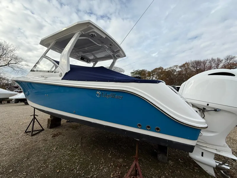 Slide: The Image of 2018 Edgewater 262 CX boat with blue hull, on stands, outdoors. - 5