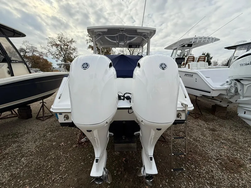 Slide: The Image of 2018 Edgewater 262 CX boat with dual outboard engines, parked on gravel. - 6