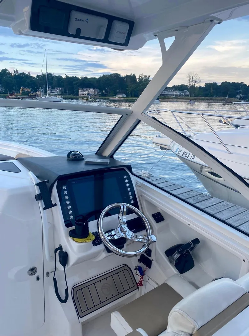 Slide: The Image of 2018 Edgewater 262 CX boat cockpit with steering wheel and navigation system, docked by the water. - 7