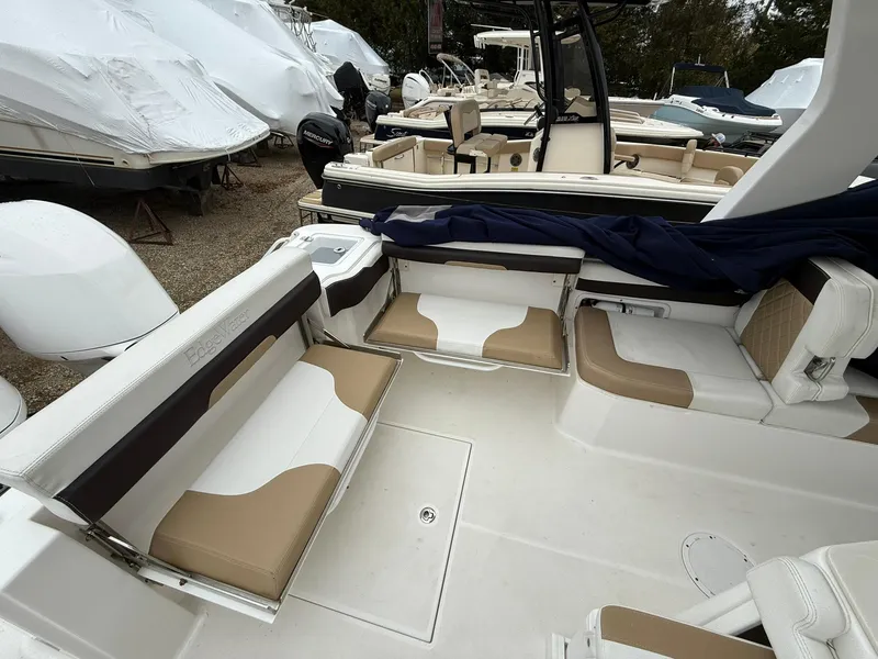 Slide: The Image of 2018 Edgewater 262 CX boat interior with beige seating, parked among other boats. - 8