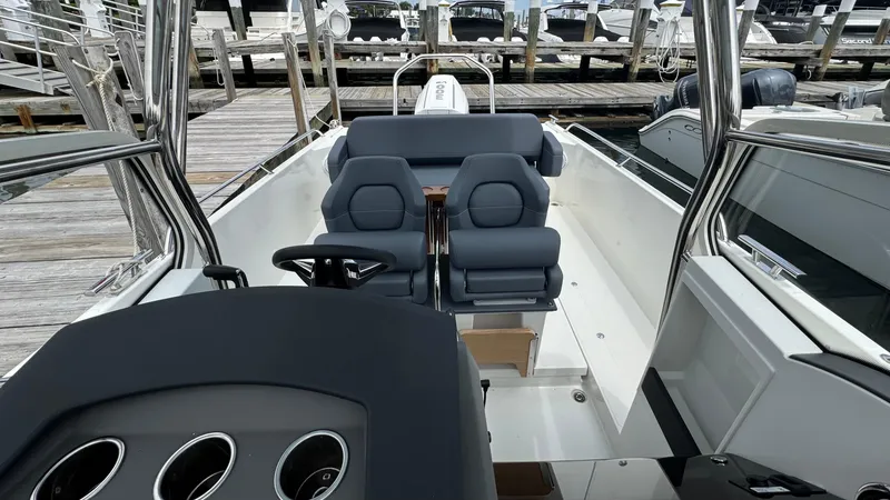 Slide: The Image of 2024 Nimbus T8 boat interior with sleek seating and modern dashboard at a marina. - 17