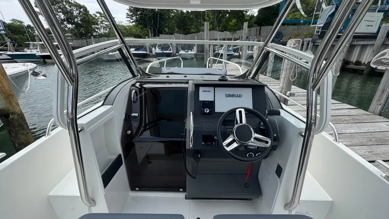 Slide: The Image of 2024 Nimbus T8 boat cockpit with steering wheel and navigation system, docked at a marina. - 14