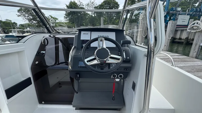 Slide: The Image of 2024 Nimbus T8 boat cockpit with steering wheel and control panel, docked at marina. - 15