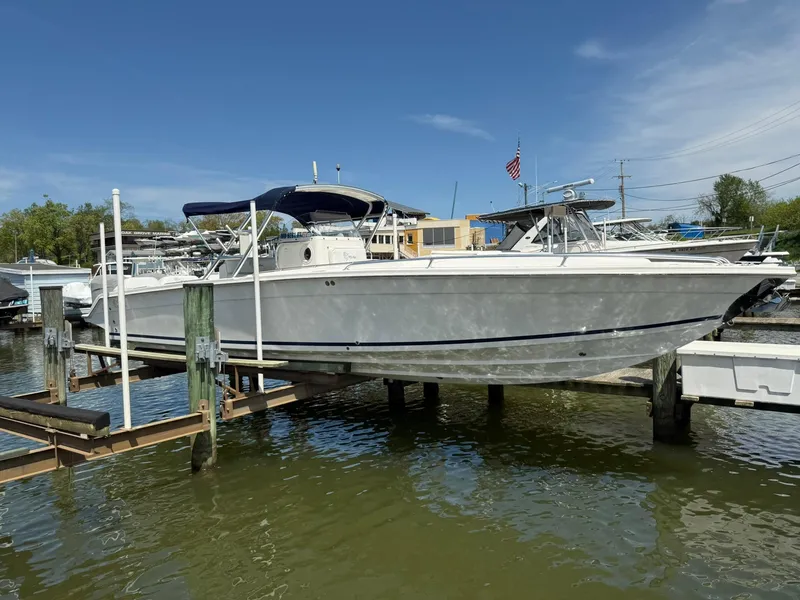 Slide: The Image of 2006 Marlago FS35 boat docked on a lift under clear blue sky. - 0