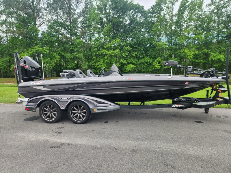 Slide: The Image of 2021 Triton 20 TRX boat on trailer, parked on road with lush green trees in background. - 15